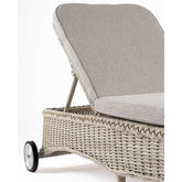 Vidéki vintage stílusú, kerekekkel felszerelt,, dönthető háttámlájú, natúr színű műrattan napozóágy, bézs színű olefin fekvőpárnával,